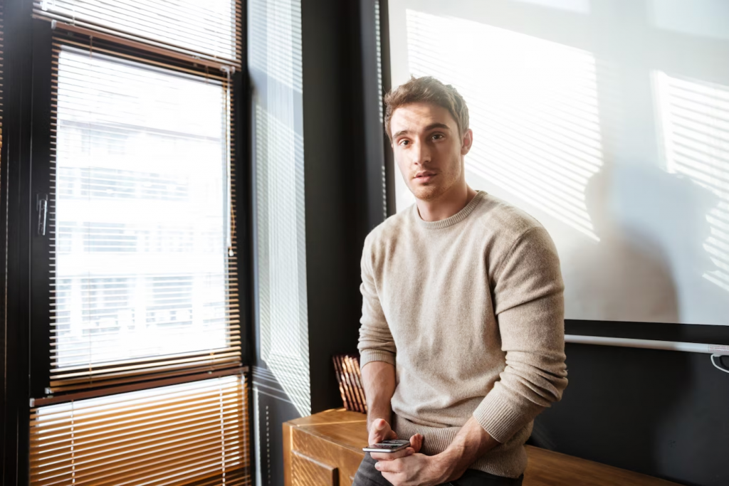 attractive young man in office looking and using phone