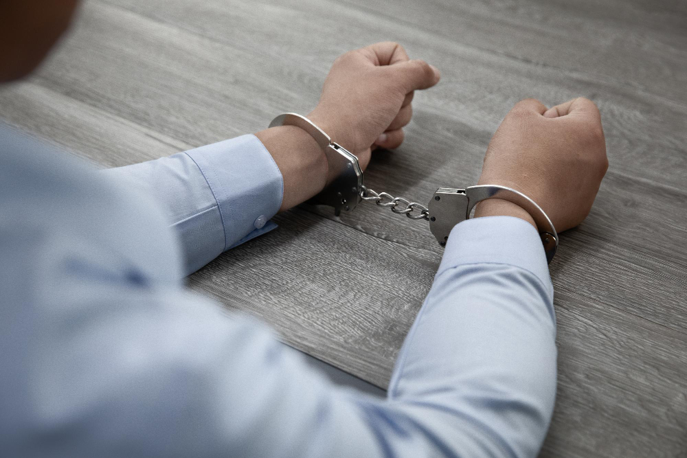 male hands in handcuffs on a wooden table