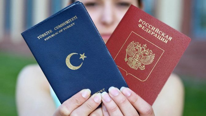 A woman holding two passports from two different countries