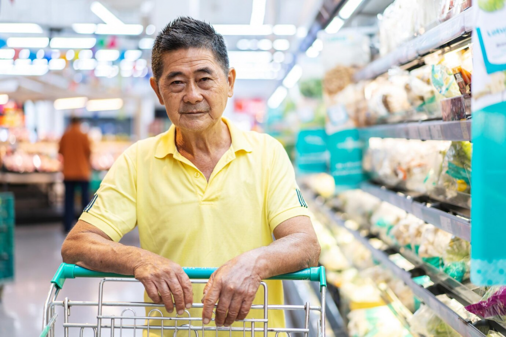 Asian senior man shopping trolley choosing other products in supermarket